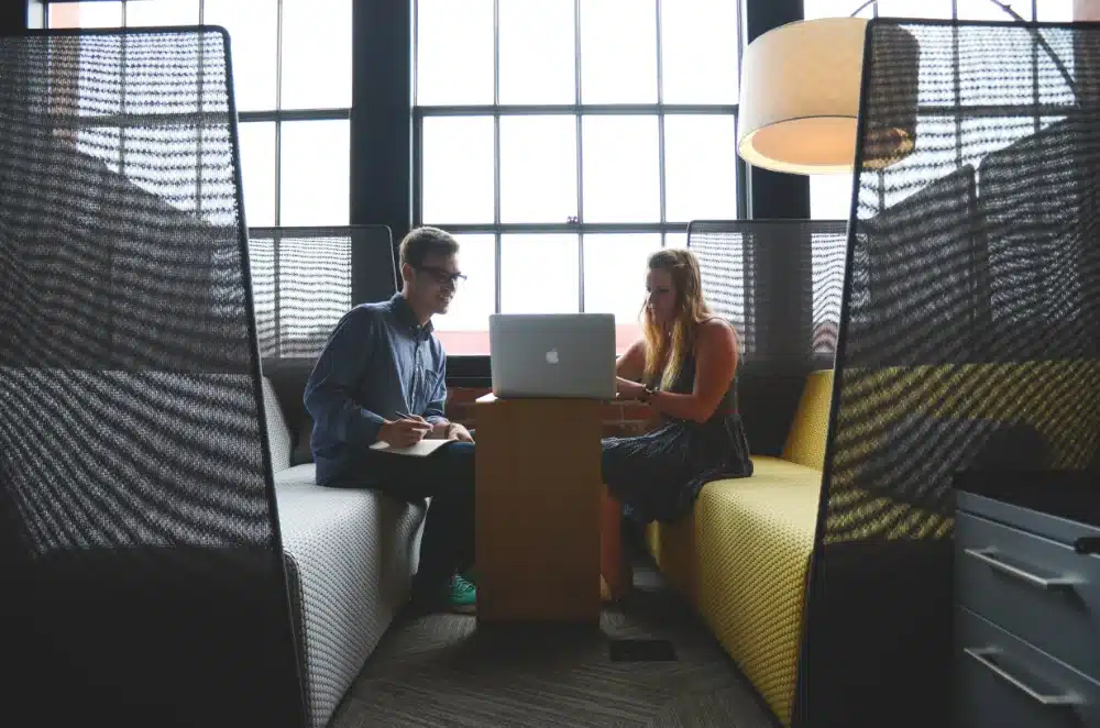 Two people working on a laptop in a co-working space
