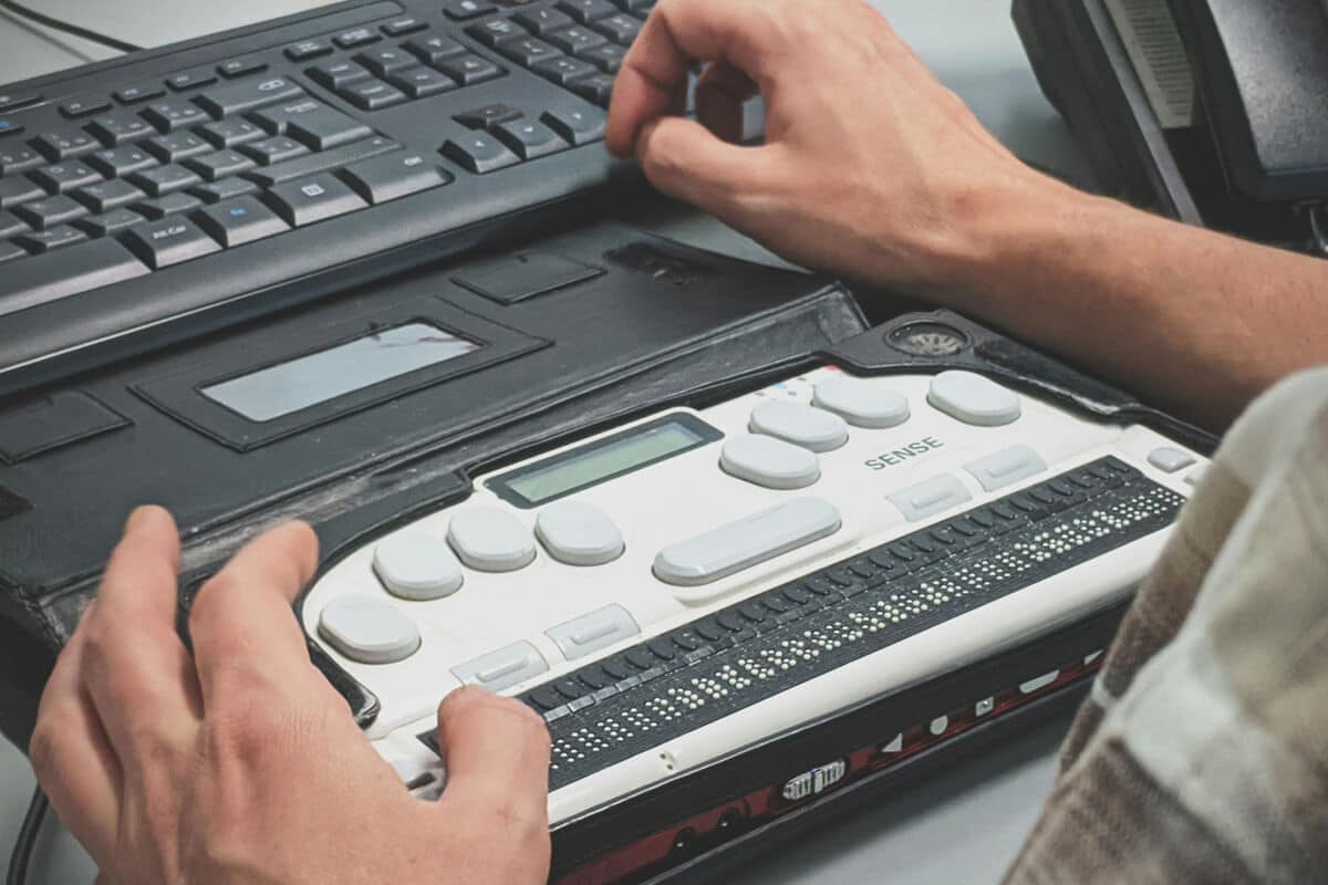 Person using a braille writer with a computer